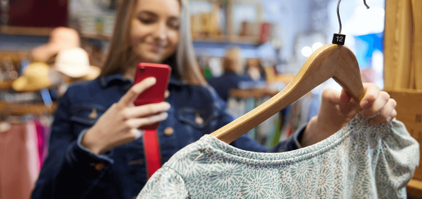 A woman taking a photo of a dress in a charity shop.