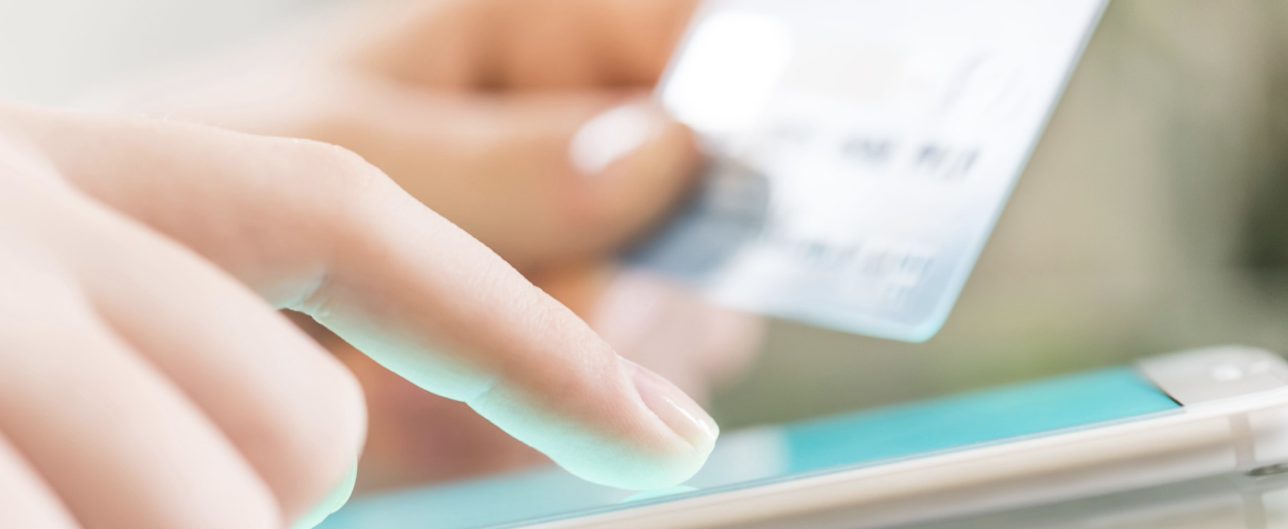 Close up of a woman's finger shopping online with a gift card using a smartphone.